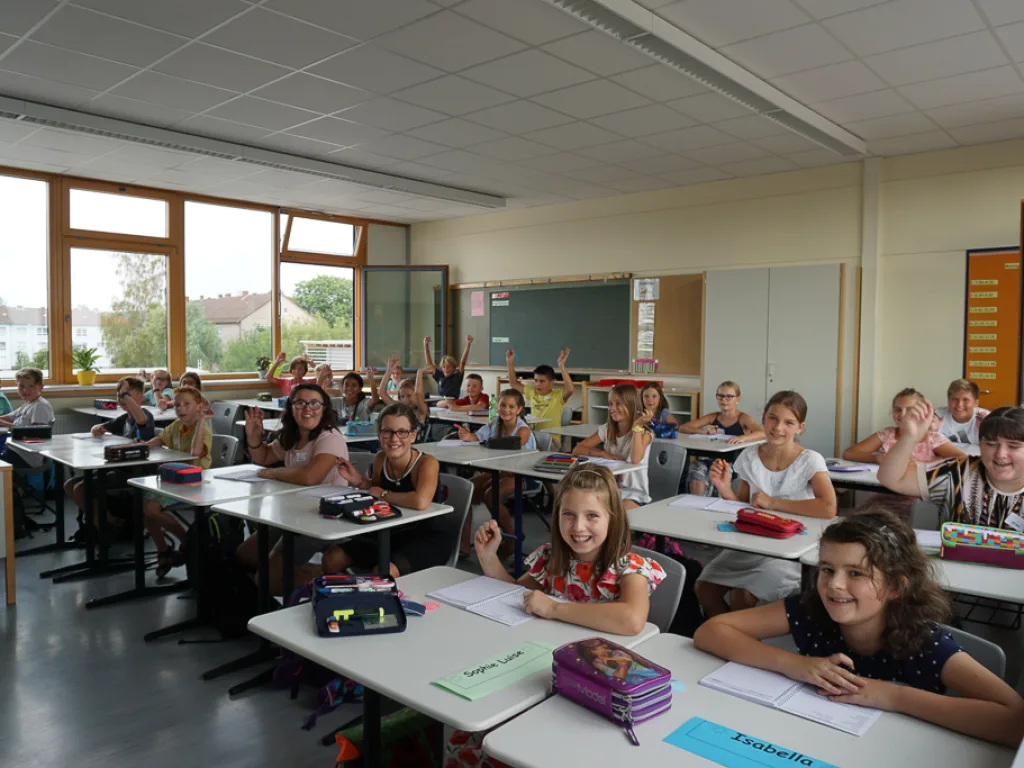 Kinder blicken von ihren Tischen zur Kamera.